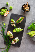 Springlike vegan nigiri sushi with smoked tofu, mushrooms and vegetables on white marble board