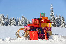 Geschenkpäckchen in farbenfrohem Papier auf Schlitten im Schnee