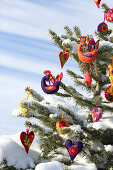 Fir tree in snowy landscape decorated with handmade felt pendants