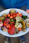 Man holding a big tray of mixed grilled vegetables