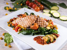 Grilled turkey steaks with spinach, zucchini, cherry tomatoes and chickpeas