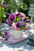 Bouquets of pansies and apple blossoms in a cup