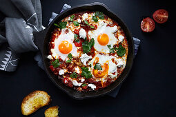Shakshuka with tomatoes, peppers, onions and eggs prepared in cast iron skillet