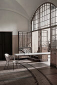 Long dining table in industrial building with vaulted ceiling and large arched doorway