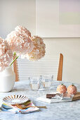 Pink flowers and glasses of water on marble breakfast table and pastries on board