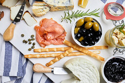 A Mediterranean appetizer platter with cheese, salmon, olives and bread sticks