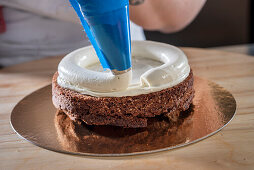 Vanillebuttercreme auf Schokoladenboden von Hochzeitstorte spritzen