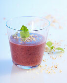 Blueberry and hazelnut smoothie with apple and orange in a glass with lemon balm