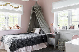 Bett mit Samtdecke und Baldachin im Mädchenzimmer in Rosa