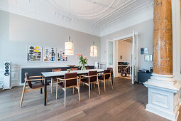 Upholstered chairs around dining table in Wilhelmine-era villa with stucco ceiling