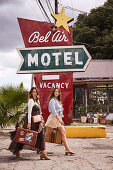 Two friends with suitcases outside a motel