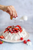 Sirup auf Pavlova mit Beeren träufeln