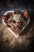 Various pine cones etc. in heart-shaped bowl