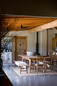 Wooden table, benches and chairs in rustic dining room with wooden ceiling beams