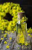 Rapeseed oil in a small bottle and rapeseed flowers