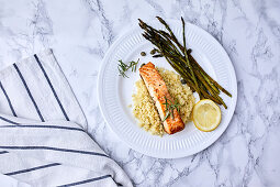 Baked salmon served on couscous with asparagus and caper on the side