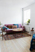 Mauve velvet sofa and oval coffee table in corner of living room