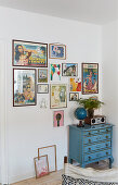 Collection of pictures on wall above blue vintage chest of drawers