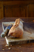 Baguette on a wooden board with a bread knife on a rustic wooden table