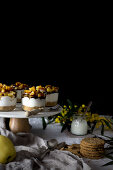 Assorted delicious desserts and snacks placed on table near napkin and flowers against black background