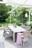 Sommerterrasse mit Sitzgruppe und Kletterrose an Pergola