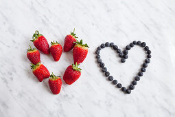 Strawberries and blueberries in heart shape, studio shot