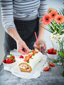 Vollkorn-Biskuitrolle mit Mascarponecreme und Erdbeeren garnieren