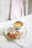 Tasse schwarzer Tee mit Zitrone und Plunderteilchen