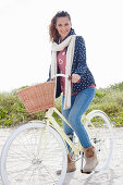 Junge Frau in Jeans, Sweatshirt, Kapuzenjacke und Pelzstiefeln auf Fahrrad