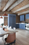 Blue cupboards and dining table in country-house kitchen of log cabin