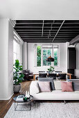 Offener Wohnraum in Grautönen mit Sofa und Esstisch im Loft