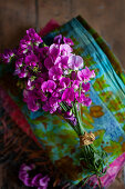 Bouquet of pink sweet peas on stack of folded fabrics