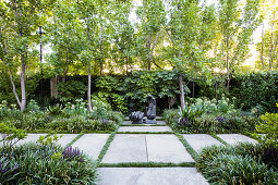 Path of large stone slabs through summer garden with sculpture