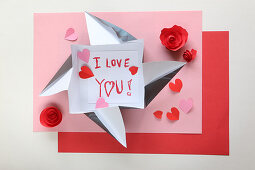 Love note in origami envelope on pink and red paper