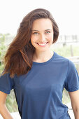 A young brunette woman wearing a short-sleeved blue t-shirt