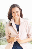 A young brunette woman wearing a blue t-shirt with a pale pink shirt blouse