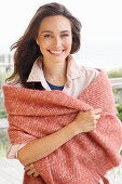 A young brunette woman wearing a light shirt blouse with a salmon pink woollen shawl