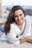 A young brunette woman wearing wearing a white tunic with a woollen jumper over her shoulders