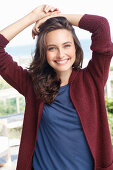 A young brunette woman wearing a blue t-shirt and a wine red cardigan