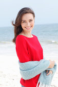 A young brunette woman wearing a red jumper with a grey woollen shawl