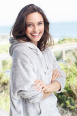 A young brunette woman wearing a light grey hoodie