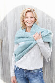 Blonde Frau in hellem Strickpullover und Wollstola