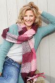 Blonde Frau in hellem Pullover, Strickjacke und dickem Schal