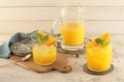 Glass and Pitcher of Orange Juice on White Background