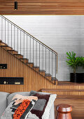 Sofa with pillows, stairs in the background, wall of stairs with wooden paneling
