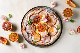Homemade Cheesecake with sicilian blood oranges, decorated by edible flowers, mint leaves and sugar powder