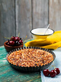 Homemade walnut tart with cherry jam, cherries, blueberries, vanilla curd on a wooden table