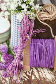 Cords and yarn in shades of purple, cow parsley and chive flowers