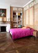 Alter Parkettboden und Wandschrank im Schlafzimmer, Bett mit pinker Wäsche