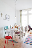 Various chairs around set table in light-flooded dining room